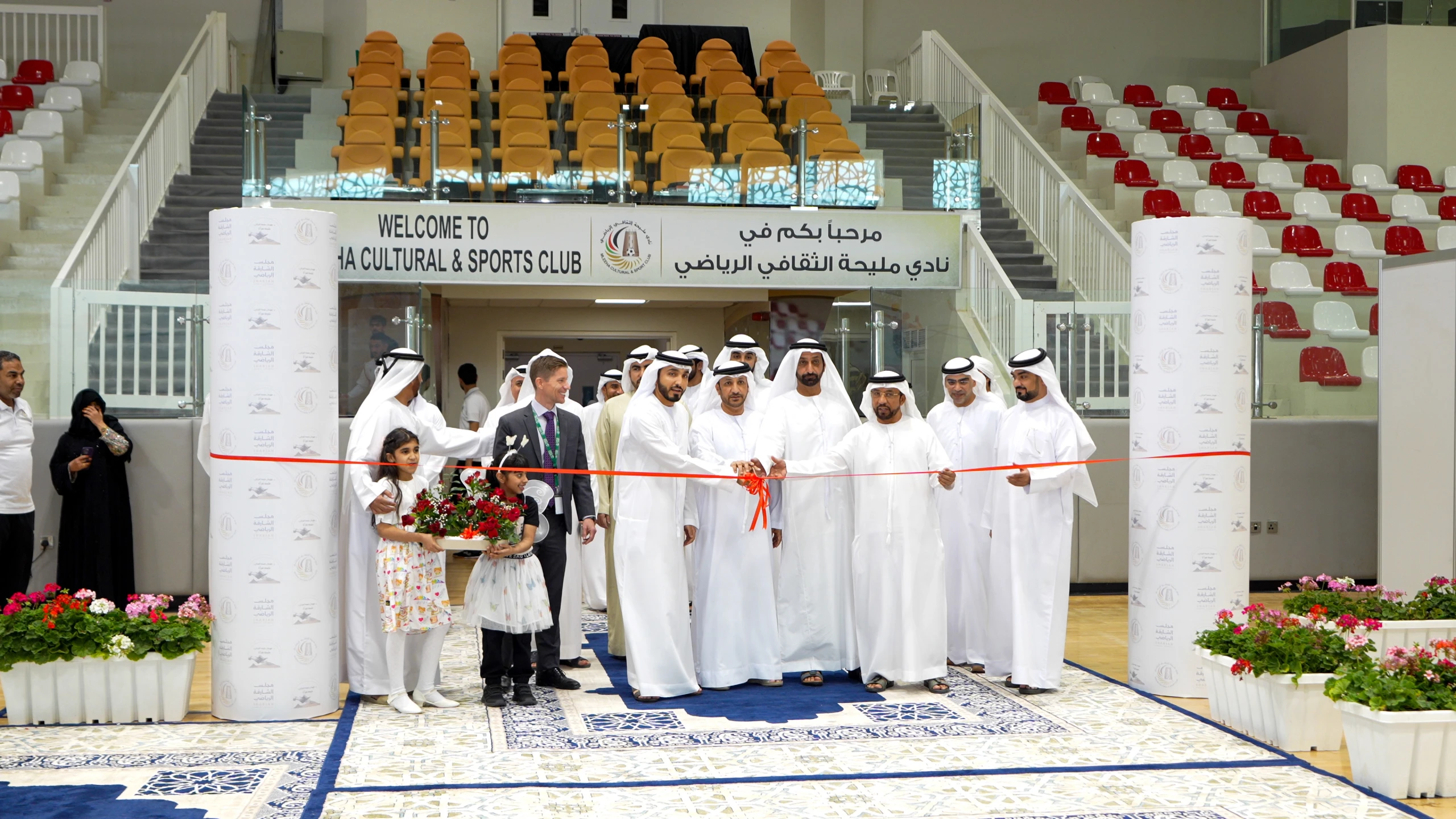Officials in kanduras cut a red ribbon at the entrance of Mleiha Cultural and Sports Club.