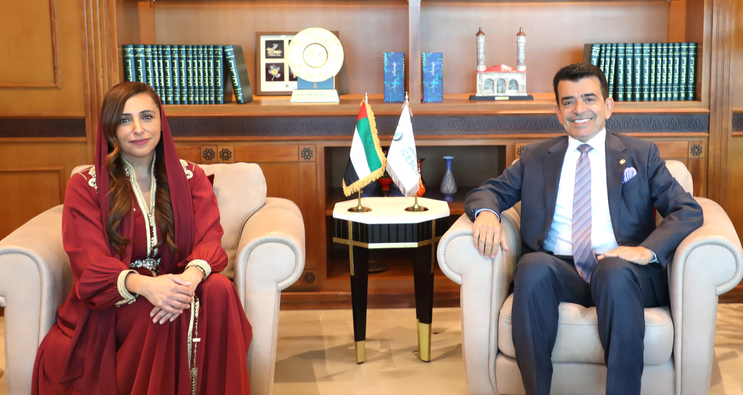 Sheikha Bodour Al Qasimi and ICESCO Director General sit smiling beside UAE and ICESCO flags.