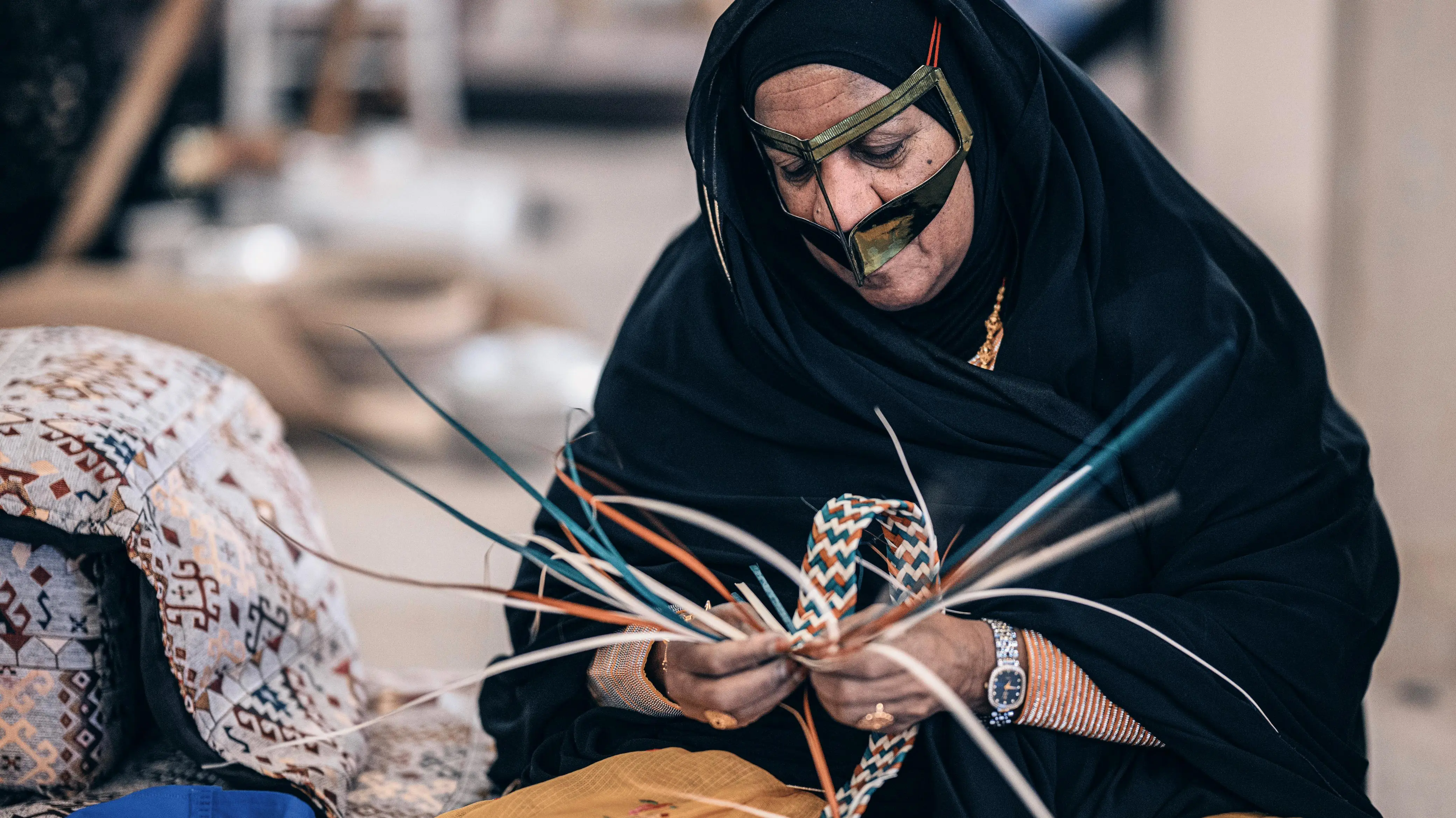 Woman in traditional battoulah weaving a colorful khoos palm-frond strap