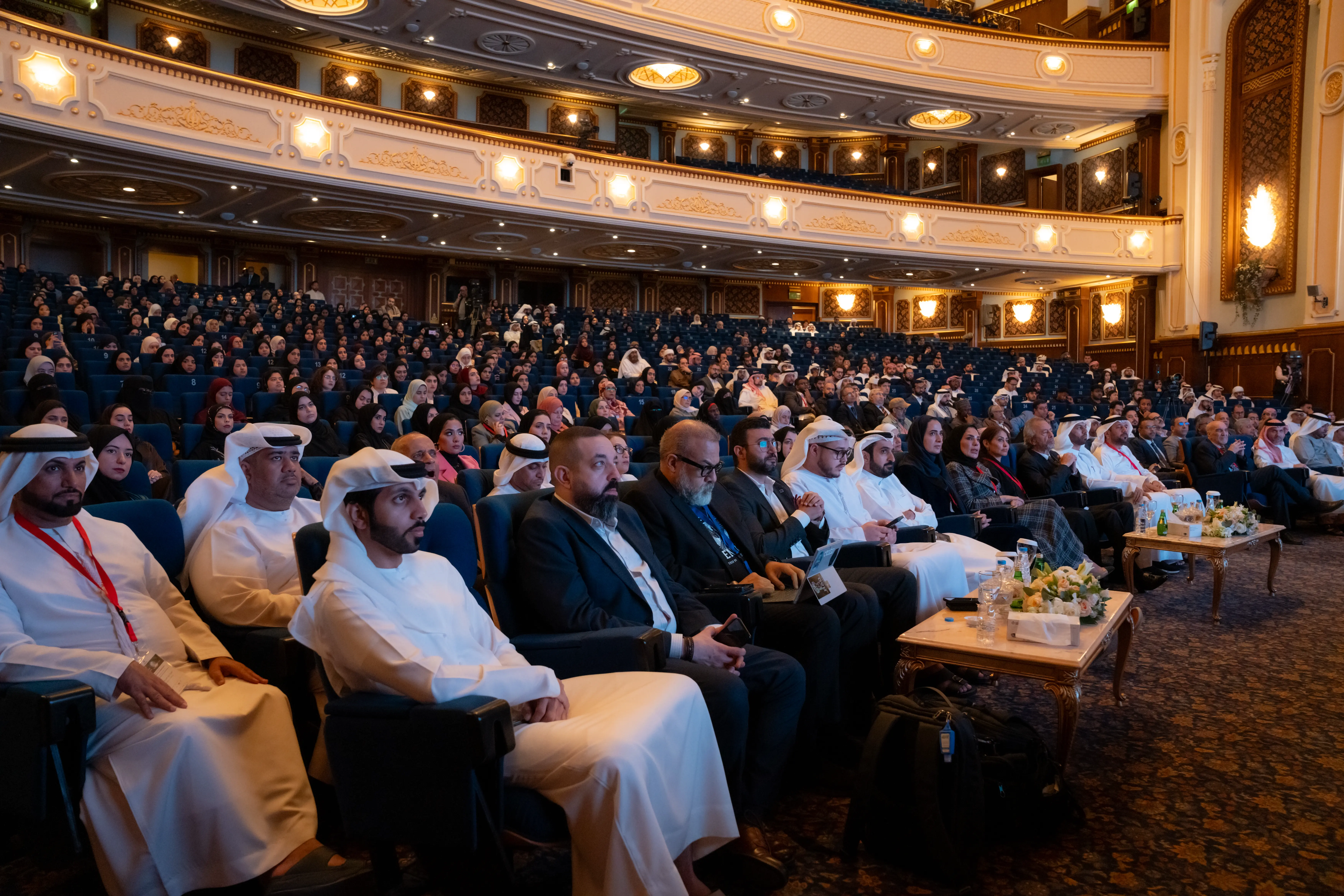 Large audience in formal attire seated in an ornate auditorium
