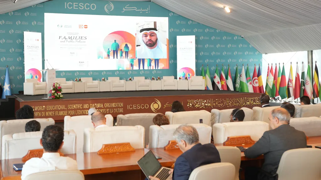 Audience members watch a speaker on the ICESCO Families conference screen, with member-state flags lining the stage.