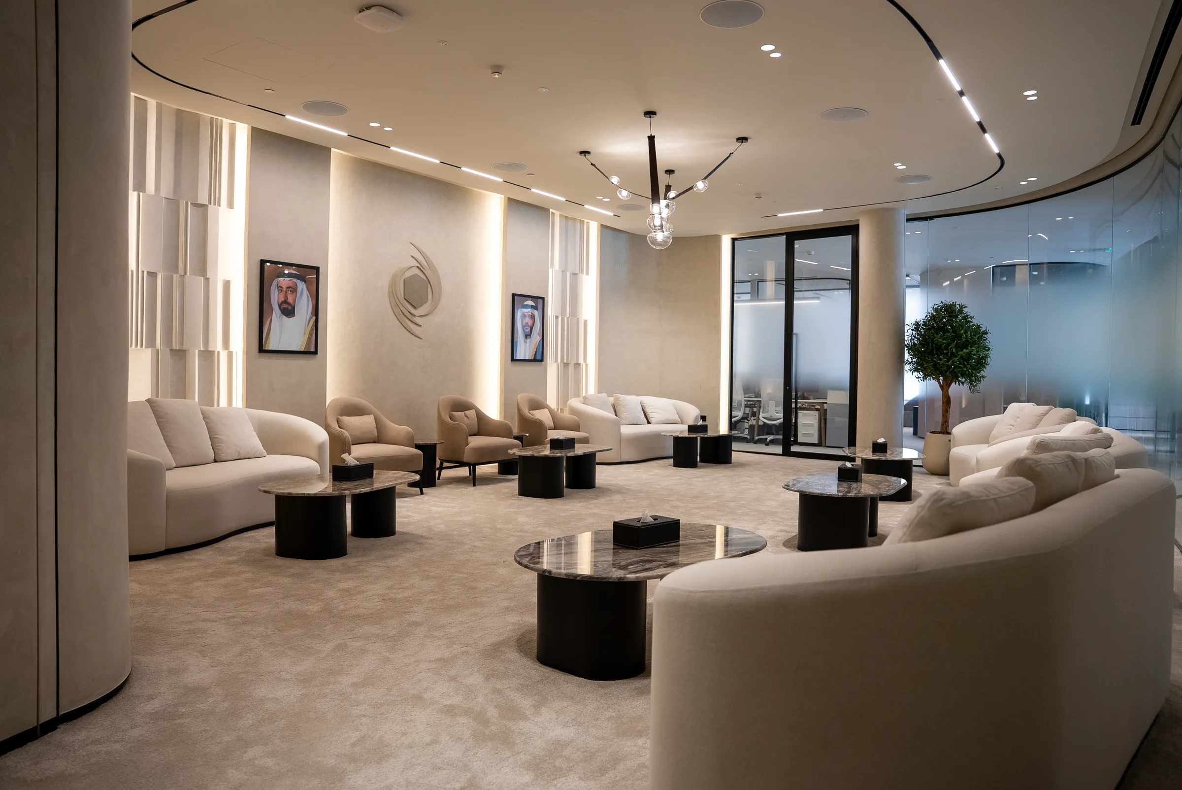 Curved sofas and marble tables fill a lounge beneath framed portraits of UAE leaders.
