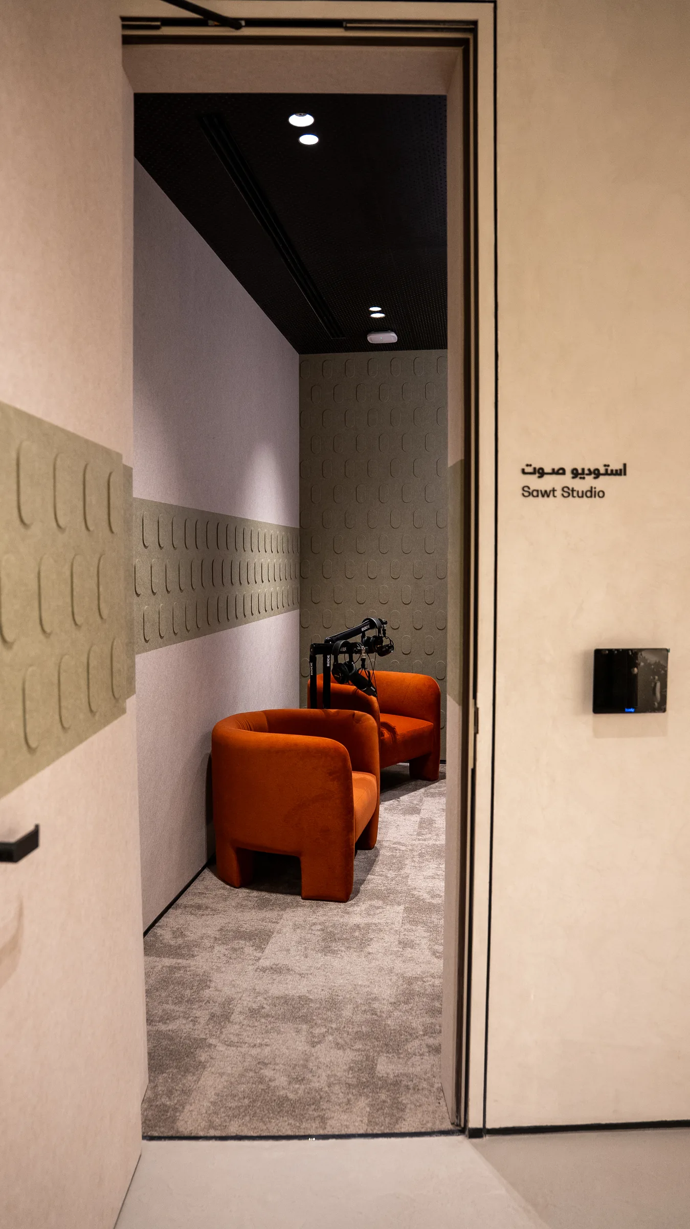 An open doorway shows Sawt Studio with orange chairs, microphones, and green acoustic panels.